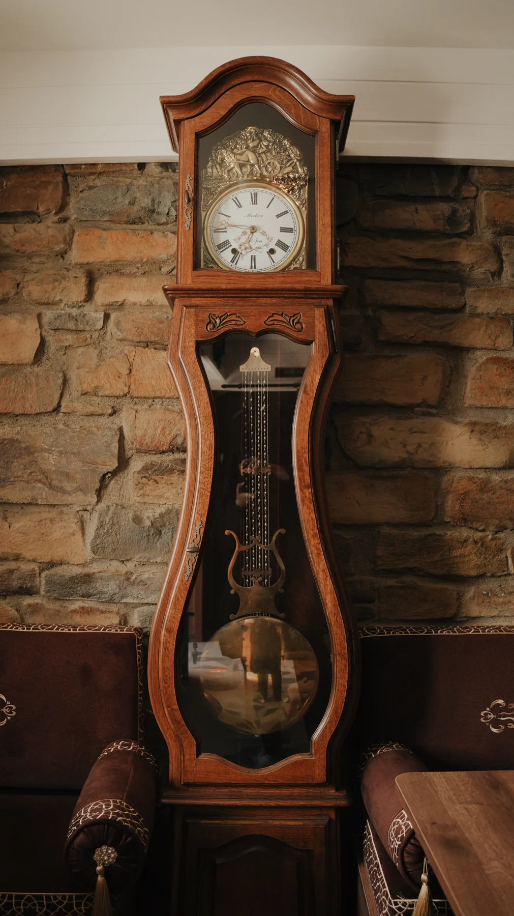 Taş duvar önündeki eski ahşap sarkaçlı saat — Paşa Konağı
